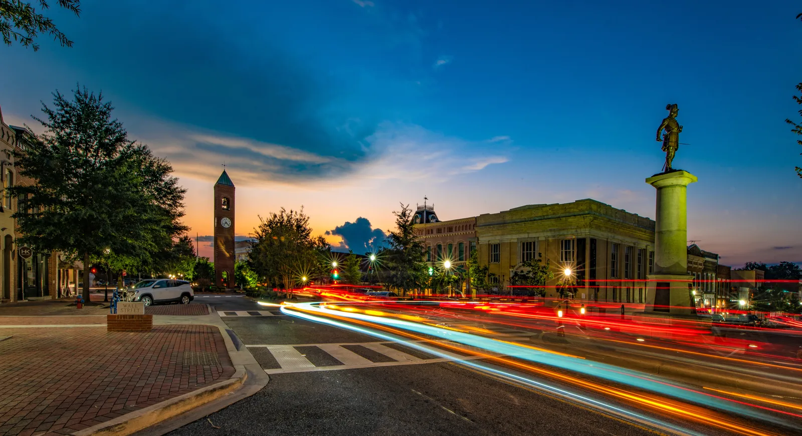 A vibrant downtown street with long-exposure traffic lights showcases Spartanburg County's focus on road infrastructure.
