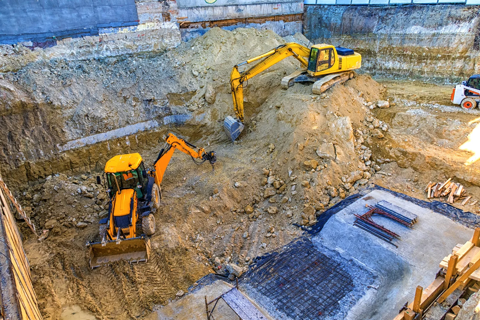 Yellow excavators working in a deep infrastructure construction pit.