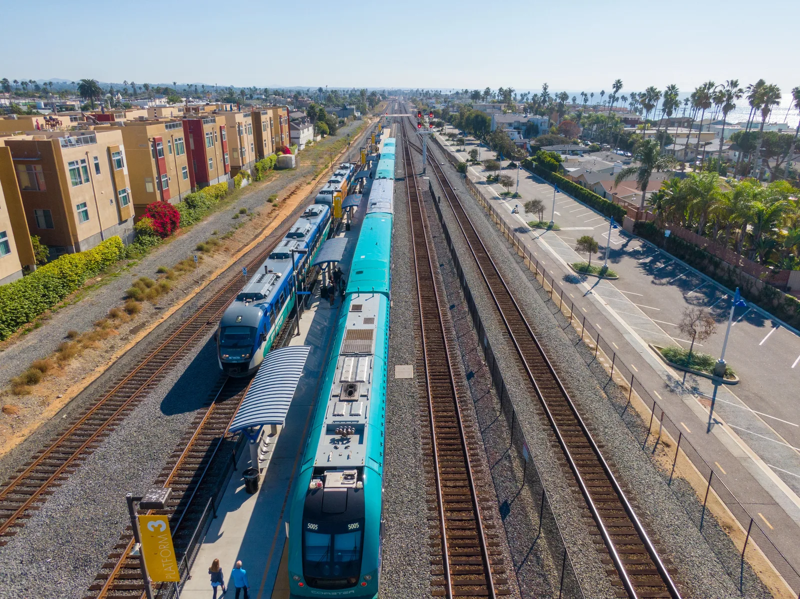 Aerial view of passenger trains at a coastal rail platform.
