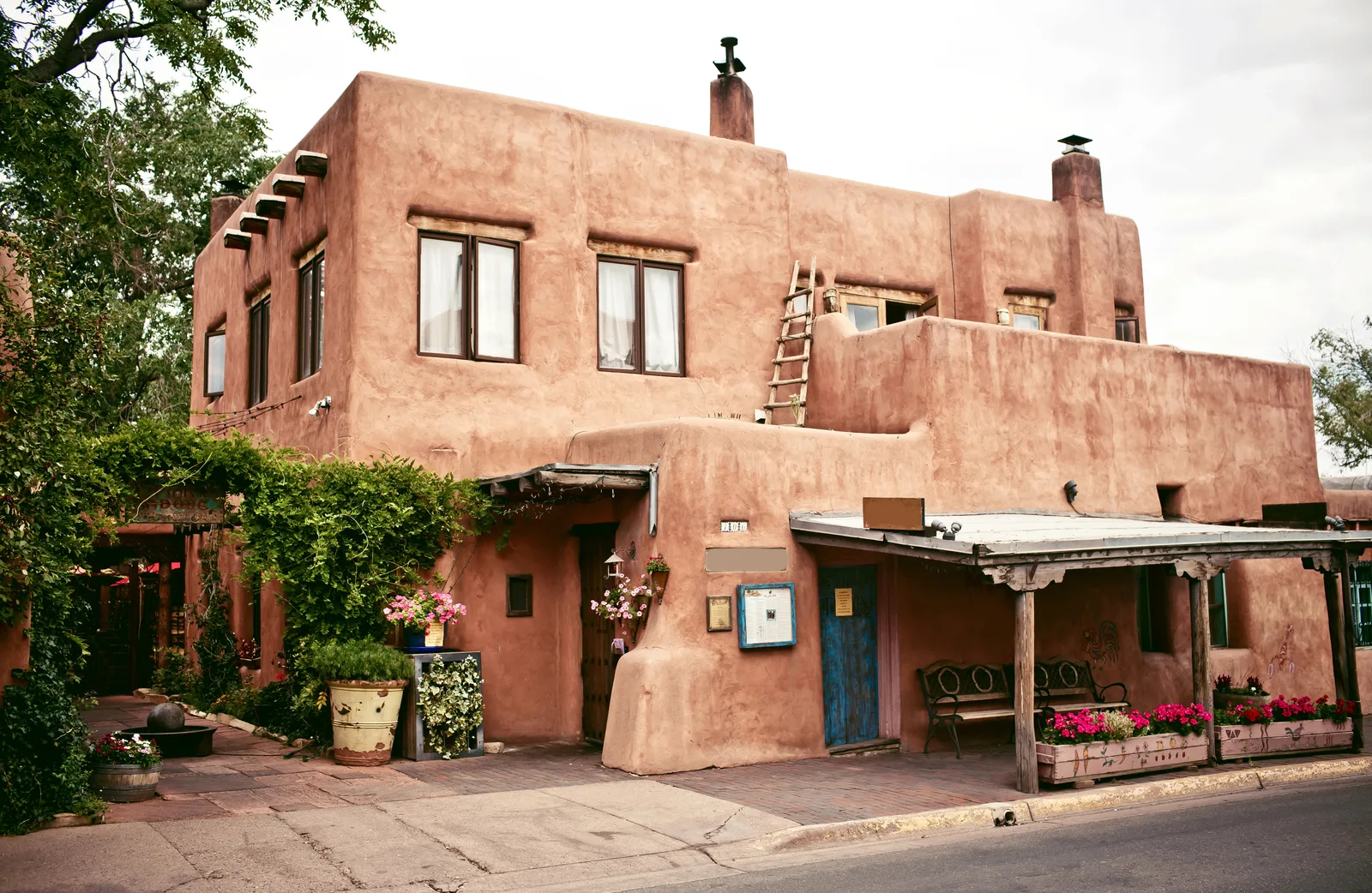 A traditional adobe building with a wooden porch and colorful flowers showcases the iconic Southwestern architecture