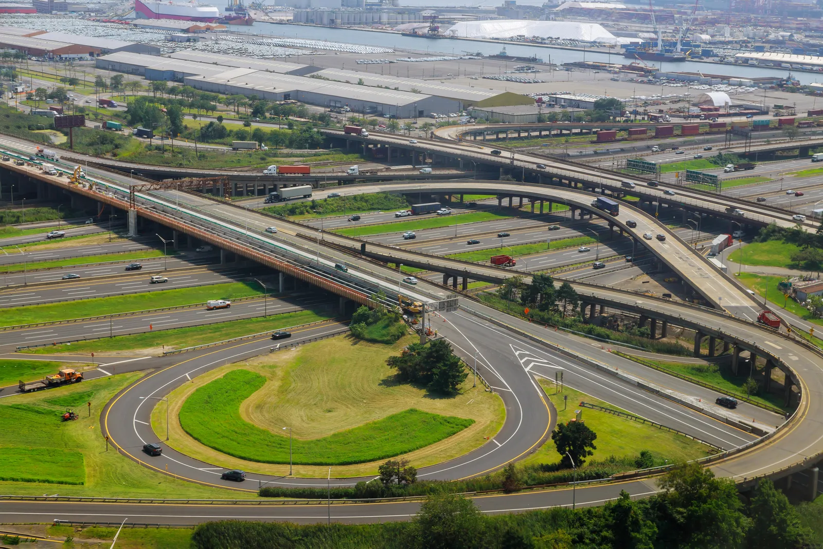 Aerial view of a multi-level highway interchange near an industrial port.