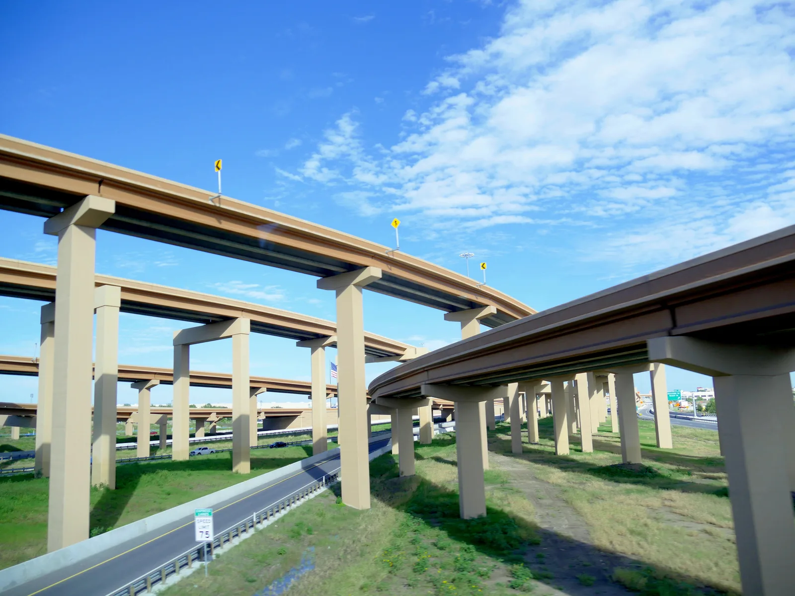 Elevated concrete highway ramps curve across a multi-level interchange under a blue sky.