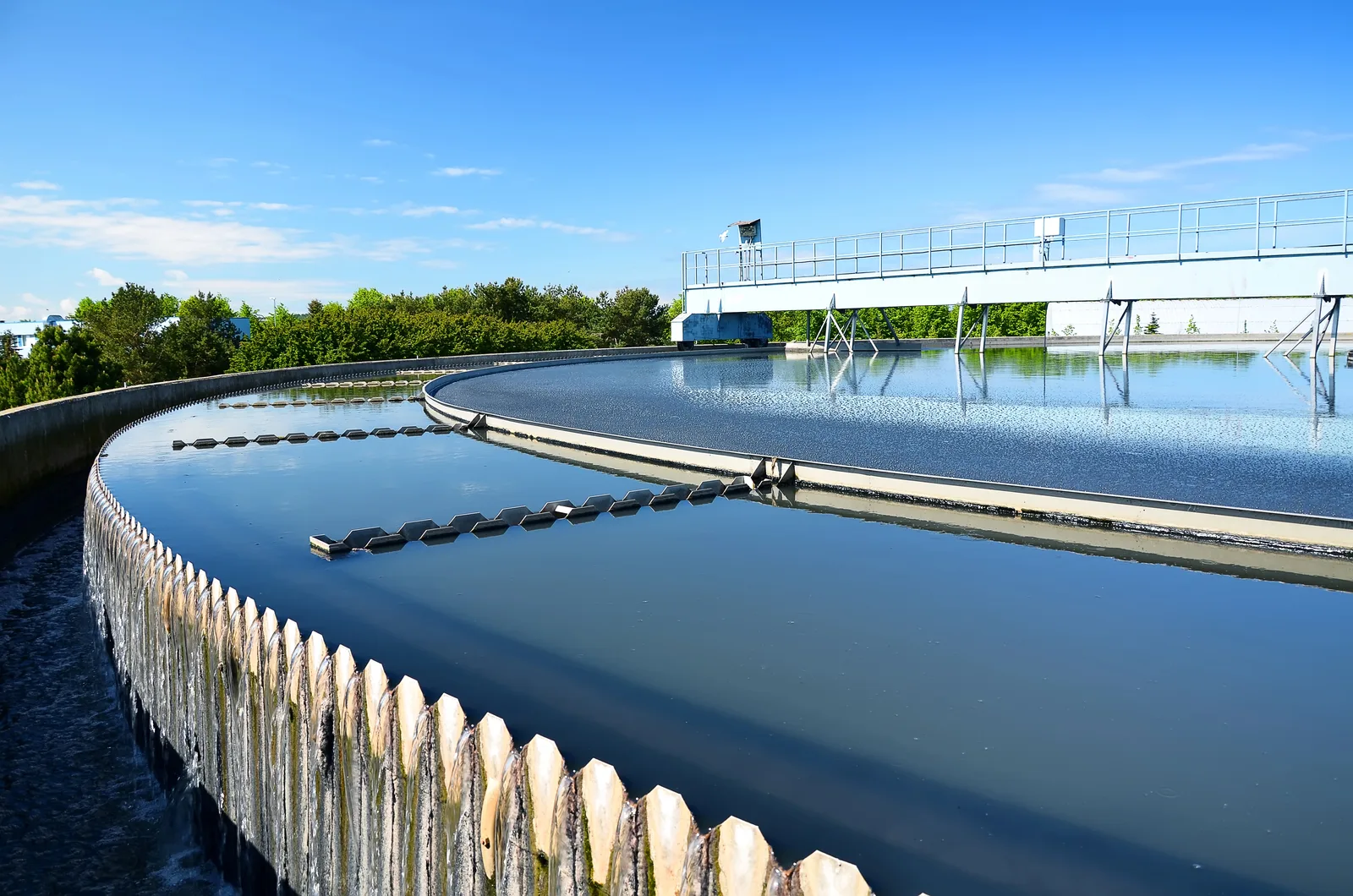 Water flows over a circular clarifier weir at a water treatment plant.