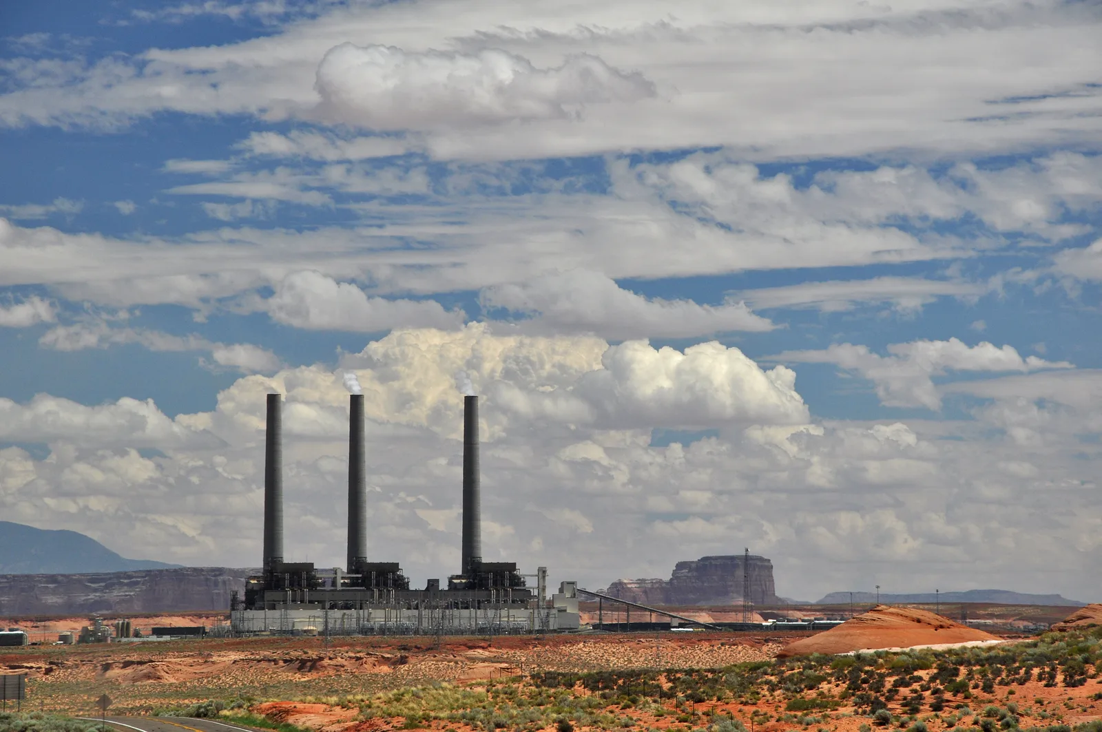 Coal-fired power plant with smokestacks set in a desert landscape.