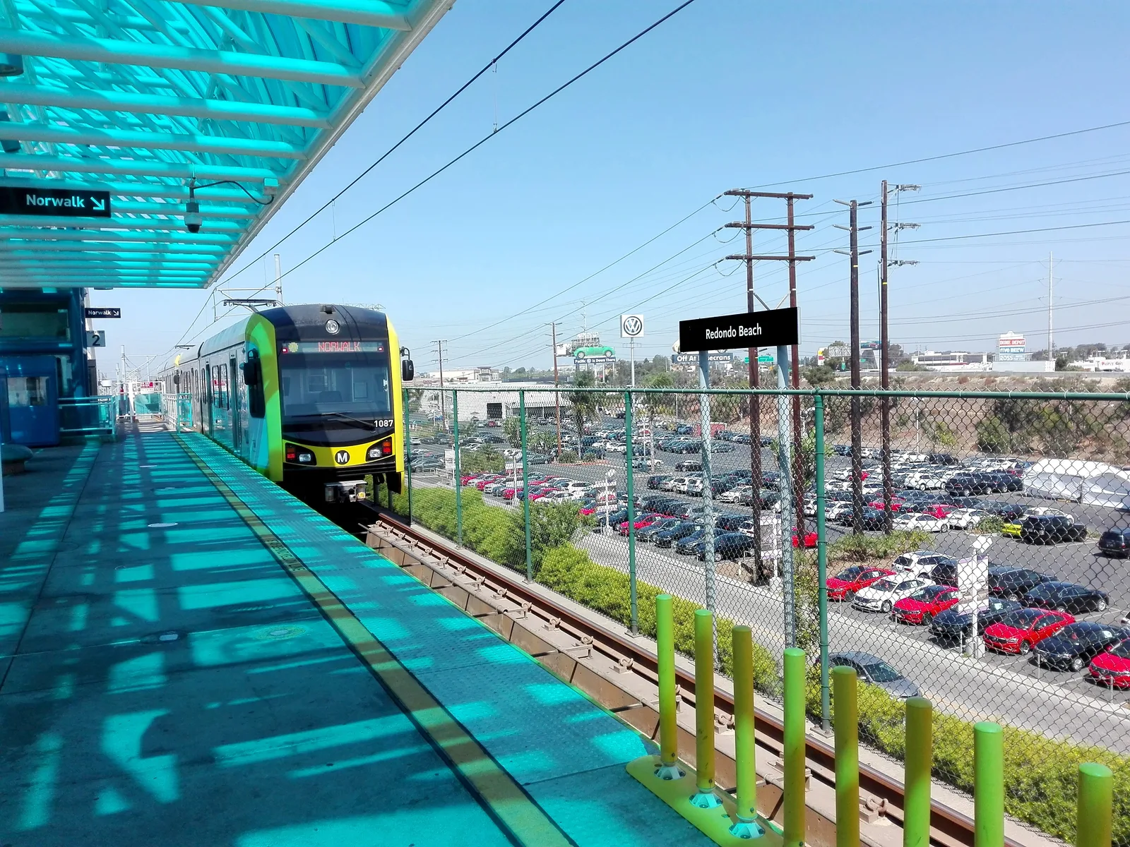 An LA Metro train arriving at an elevated transit station platform.